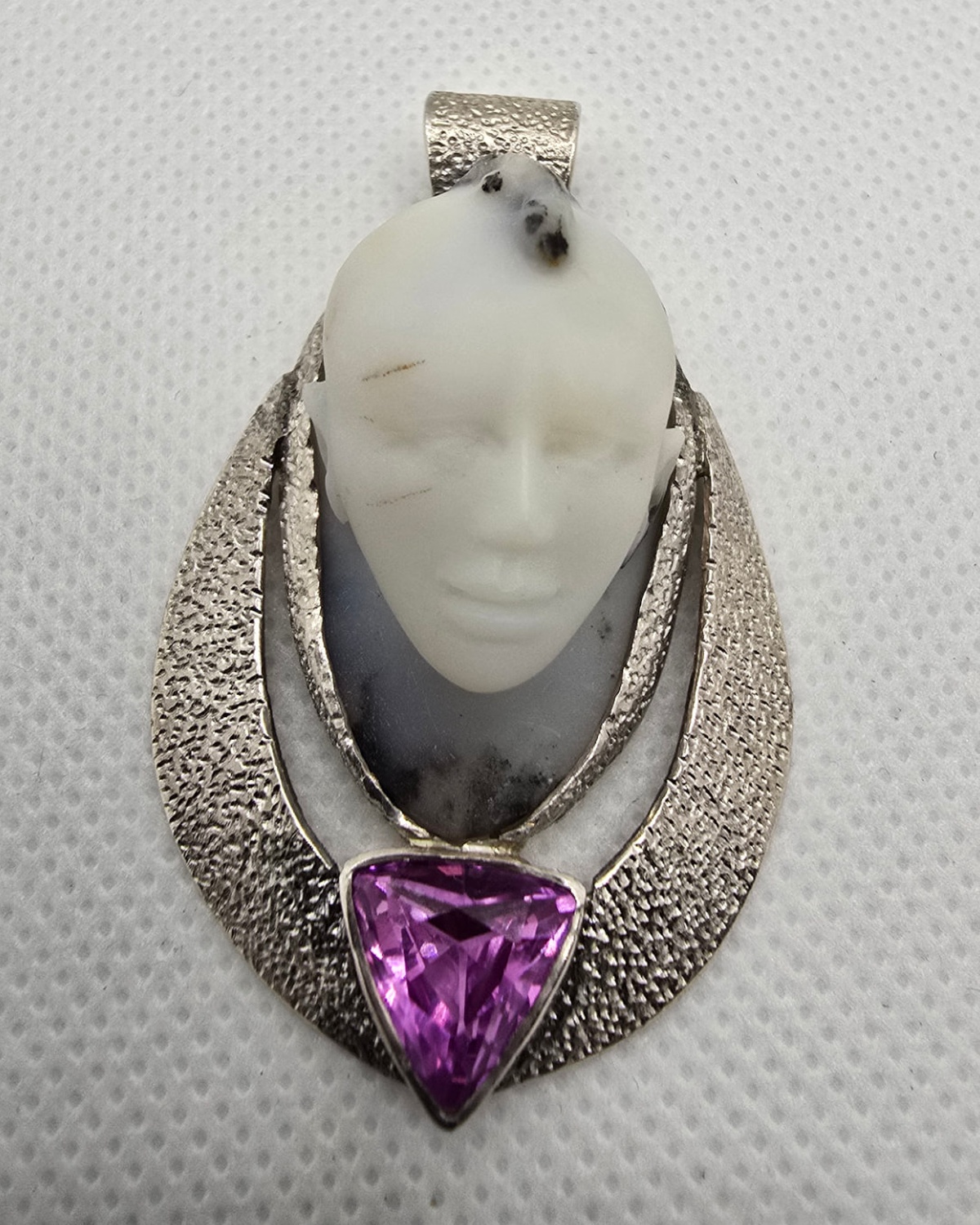 The Mystic — human face hand-carved in moss agate above a triangular faceted amethyst, framed by an open-form textured silver setting