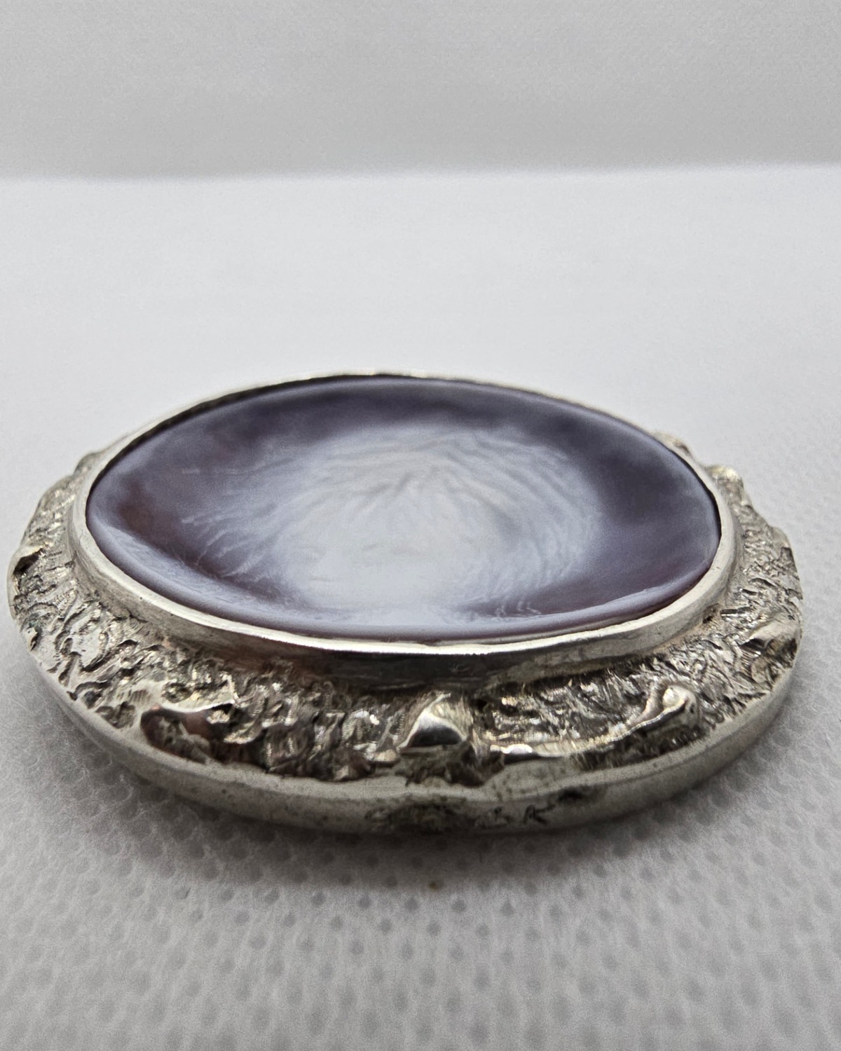 The Dreamer — low-angle profile view showing shell thickness, raised oval form and textured silverwork