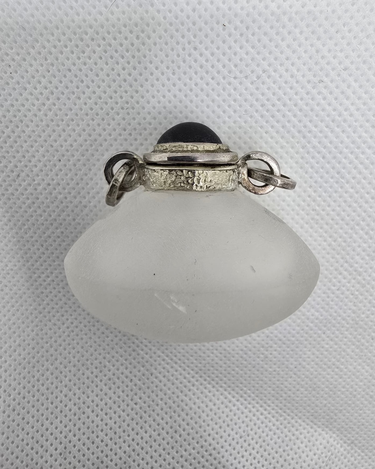 Frosted rock crystal vessel seen from above, silver collar and dark cabochon stopper