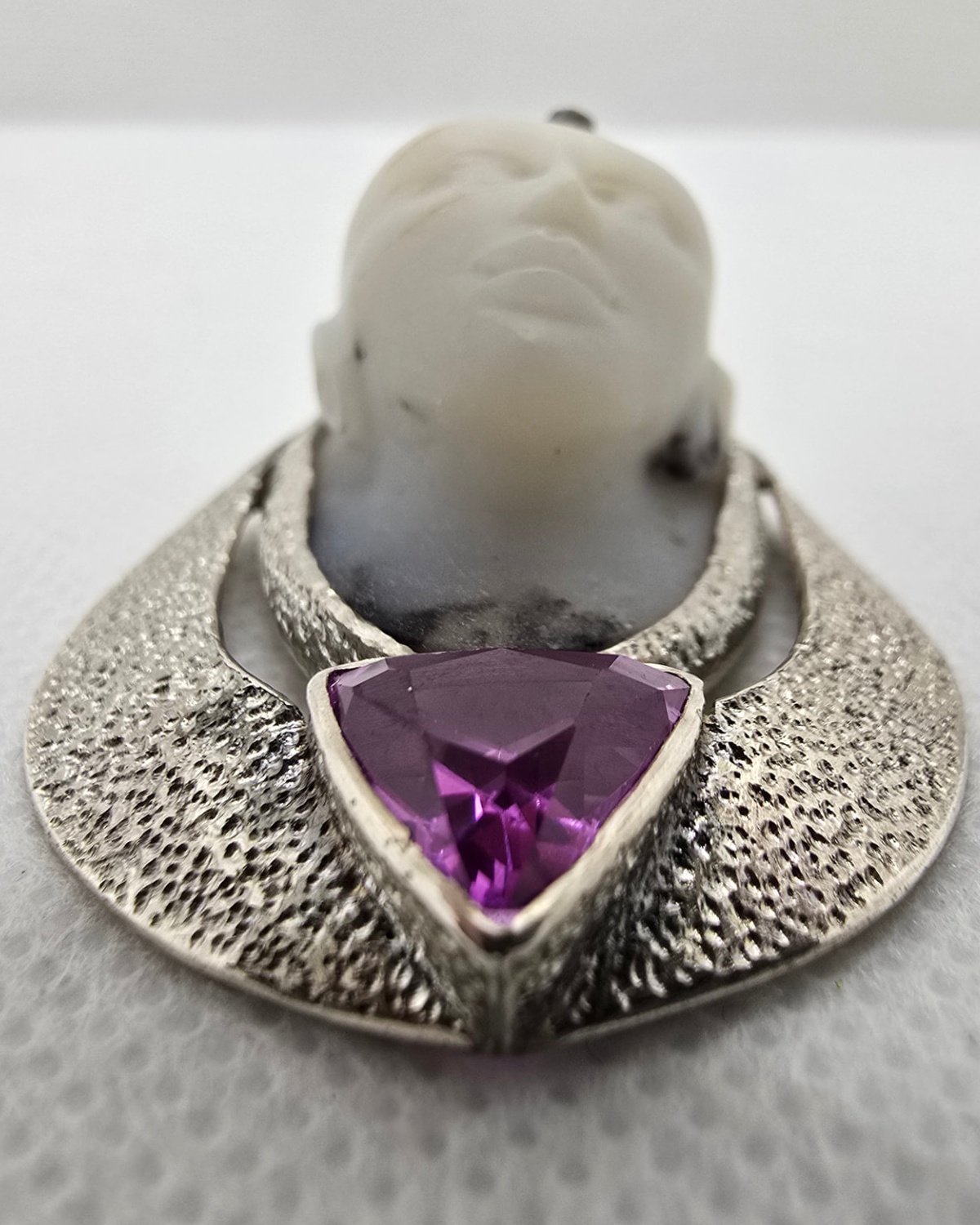 The Mystic — low-angle view showing the exceptional depth of the carved face and the faceting of the amethyst