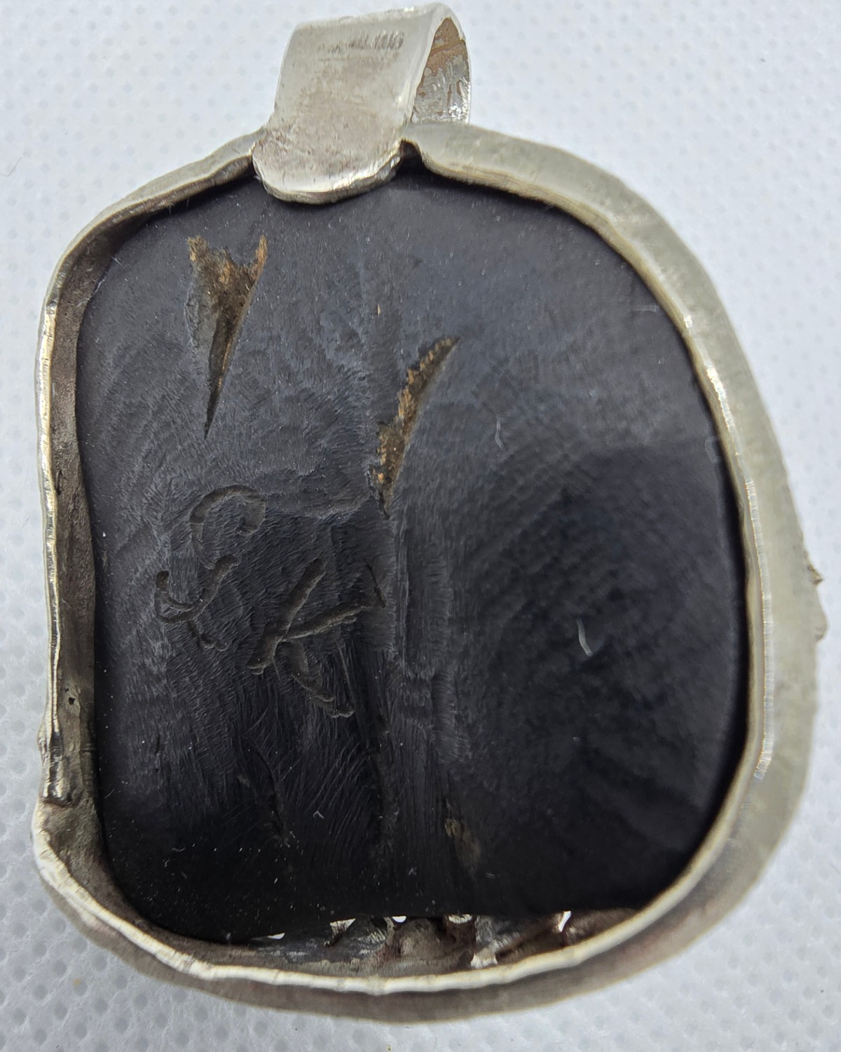 The Daughter of the Earth — reverse showing the dark natural material and the handmade construction of the silver frame and bail