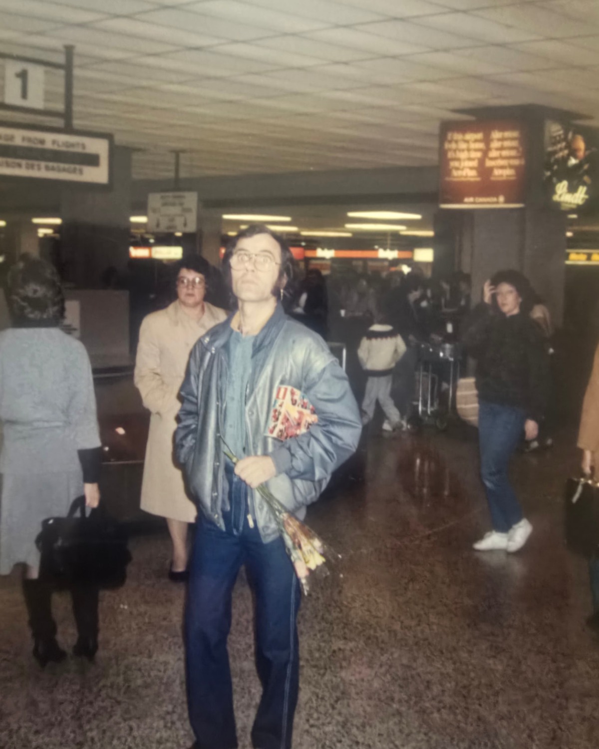 Grzegorz Kiernicki holding flowers in an airport arrivals hall after emigrating to Canada