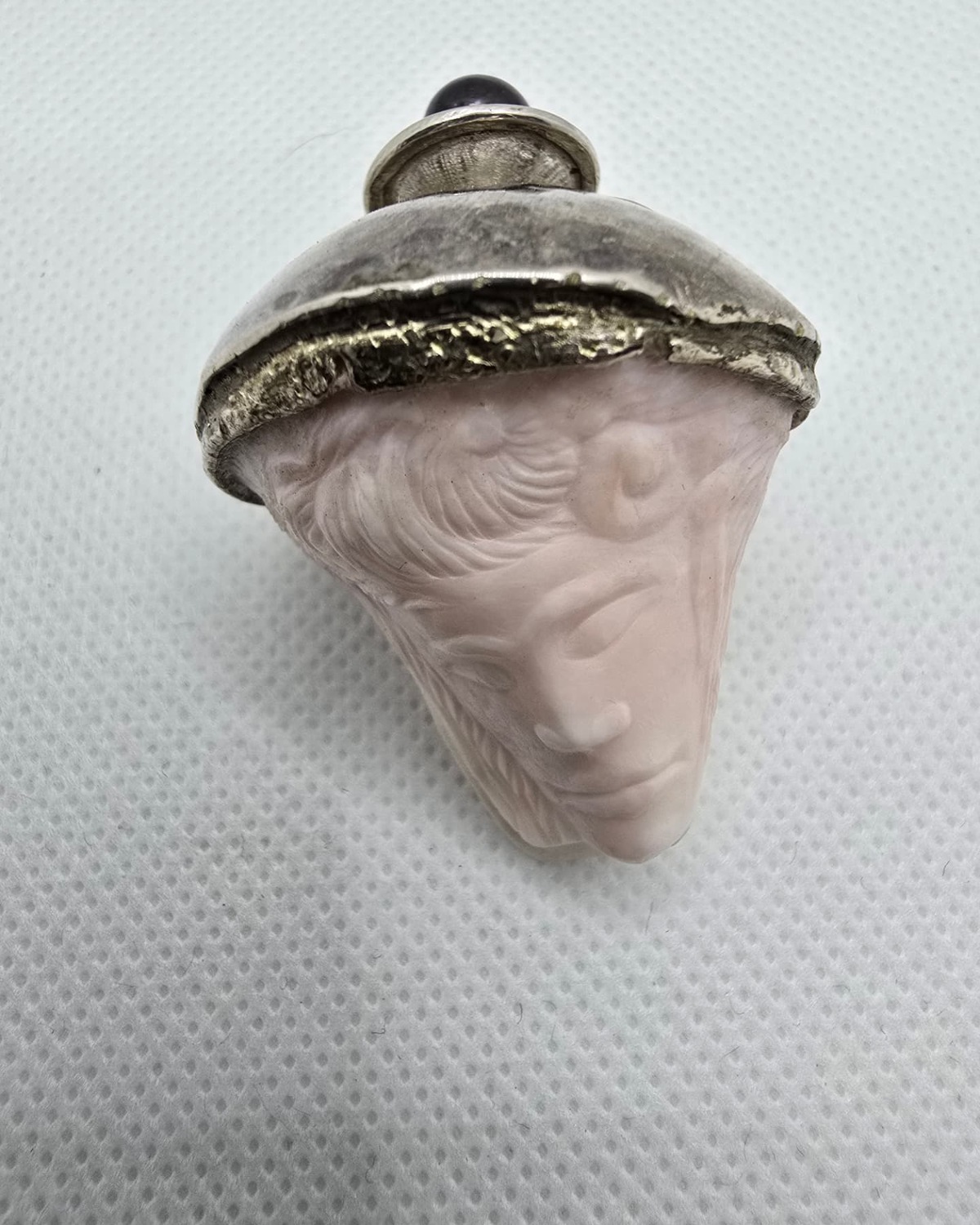 Rose quartz vessel carved as a veiled face beneath a domed silver cap, front view