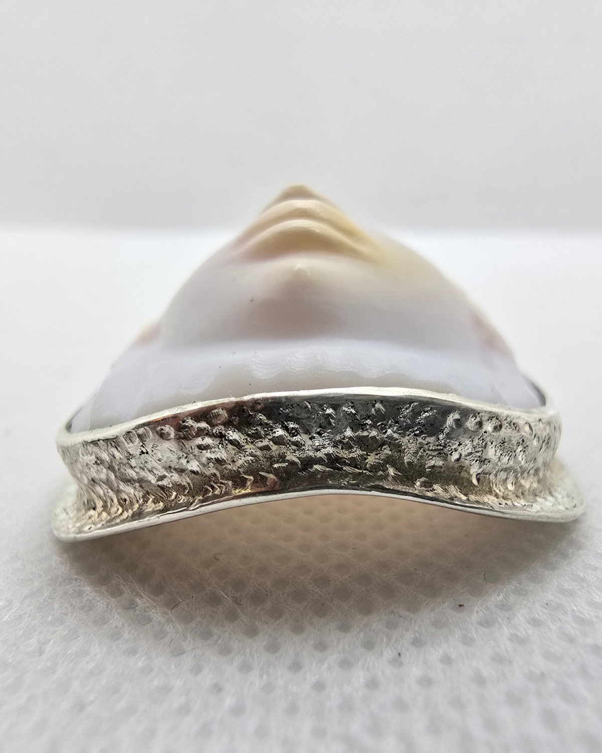 Serenity — low-angle view showing the depth of the carved face, shell thickness and textured silverwork