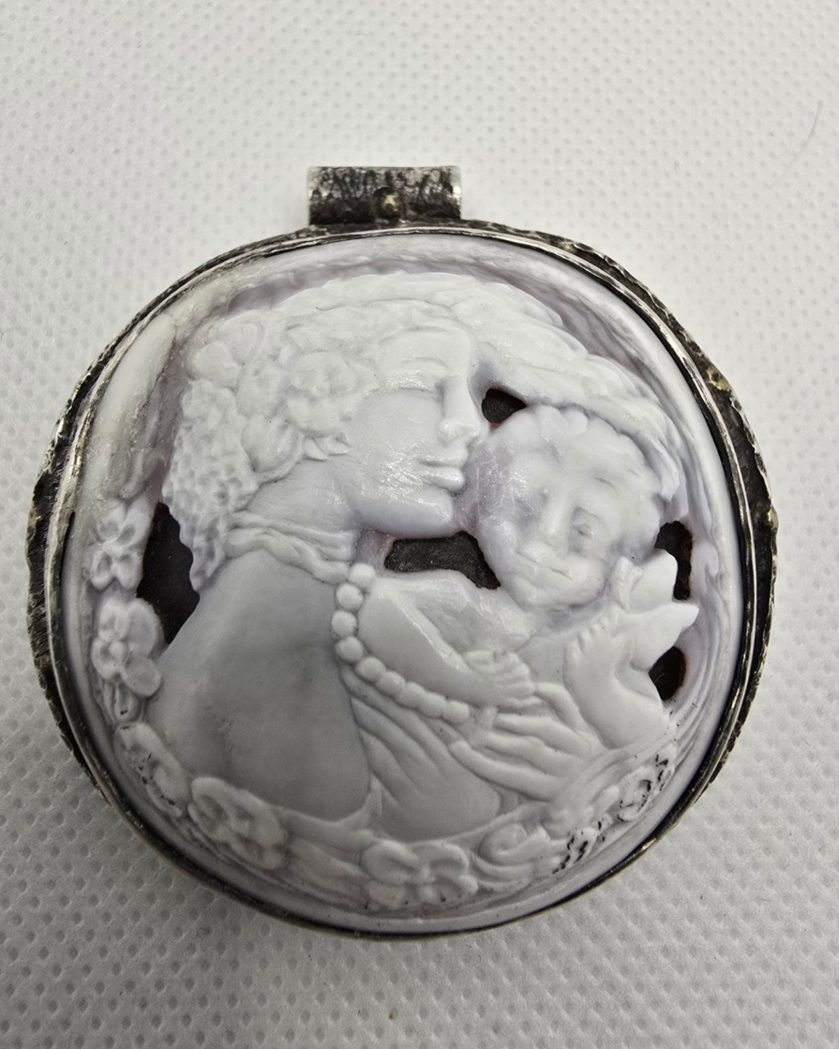 Mother and Child — hand-carved natural shell high-relief cameo of a mother holding her baby surrounded by carved flowers, in a handcrafted textured silver setting