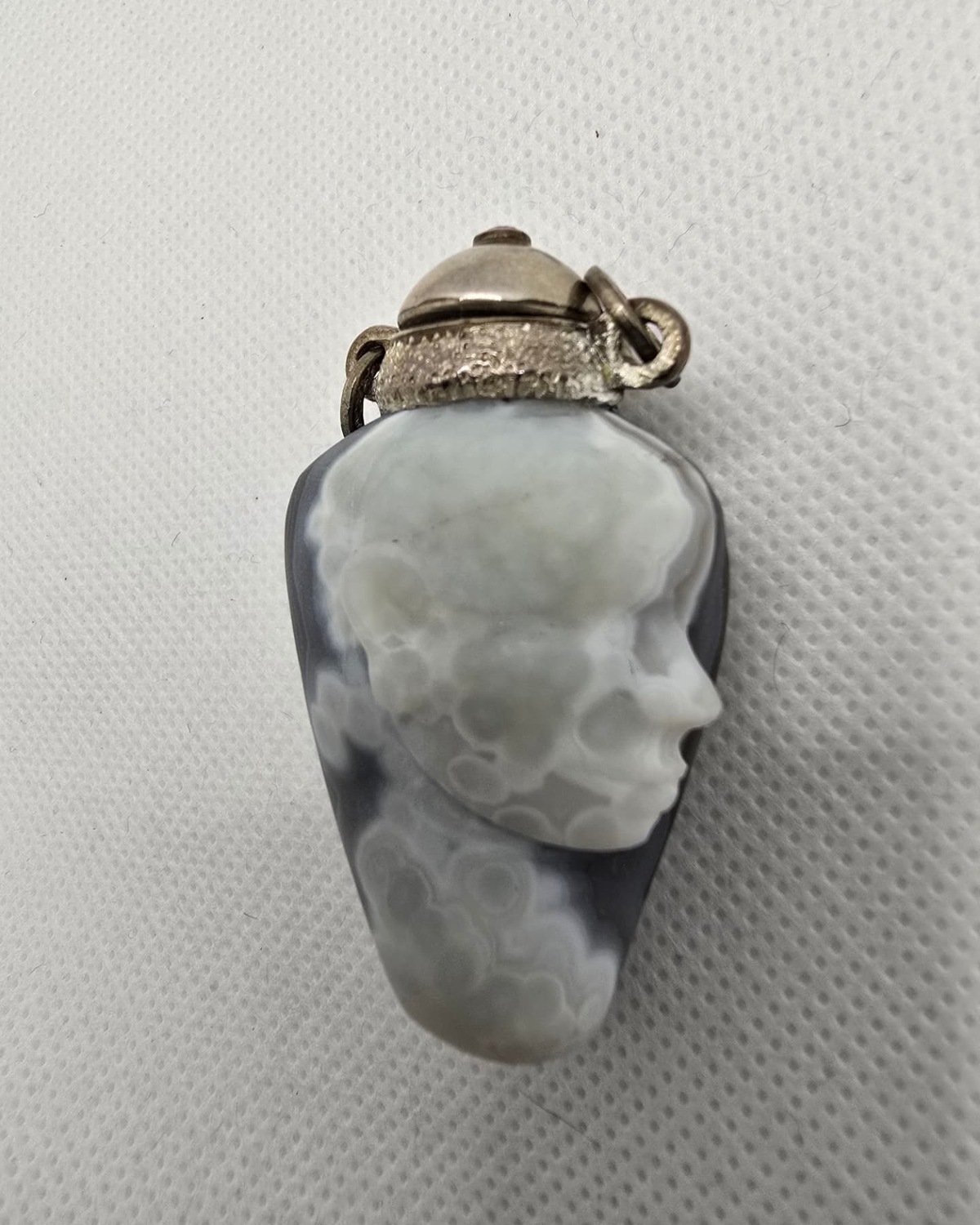 Hand-carved agate vessel with sculpted face in profile and silver collar, front view