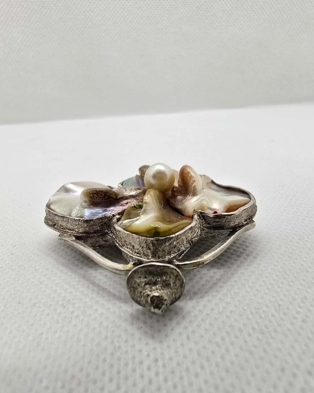 Mother-of-pearl petal vessel in profile showing the silver stopper and shell petals