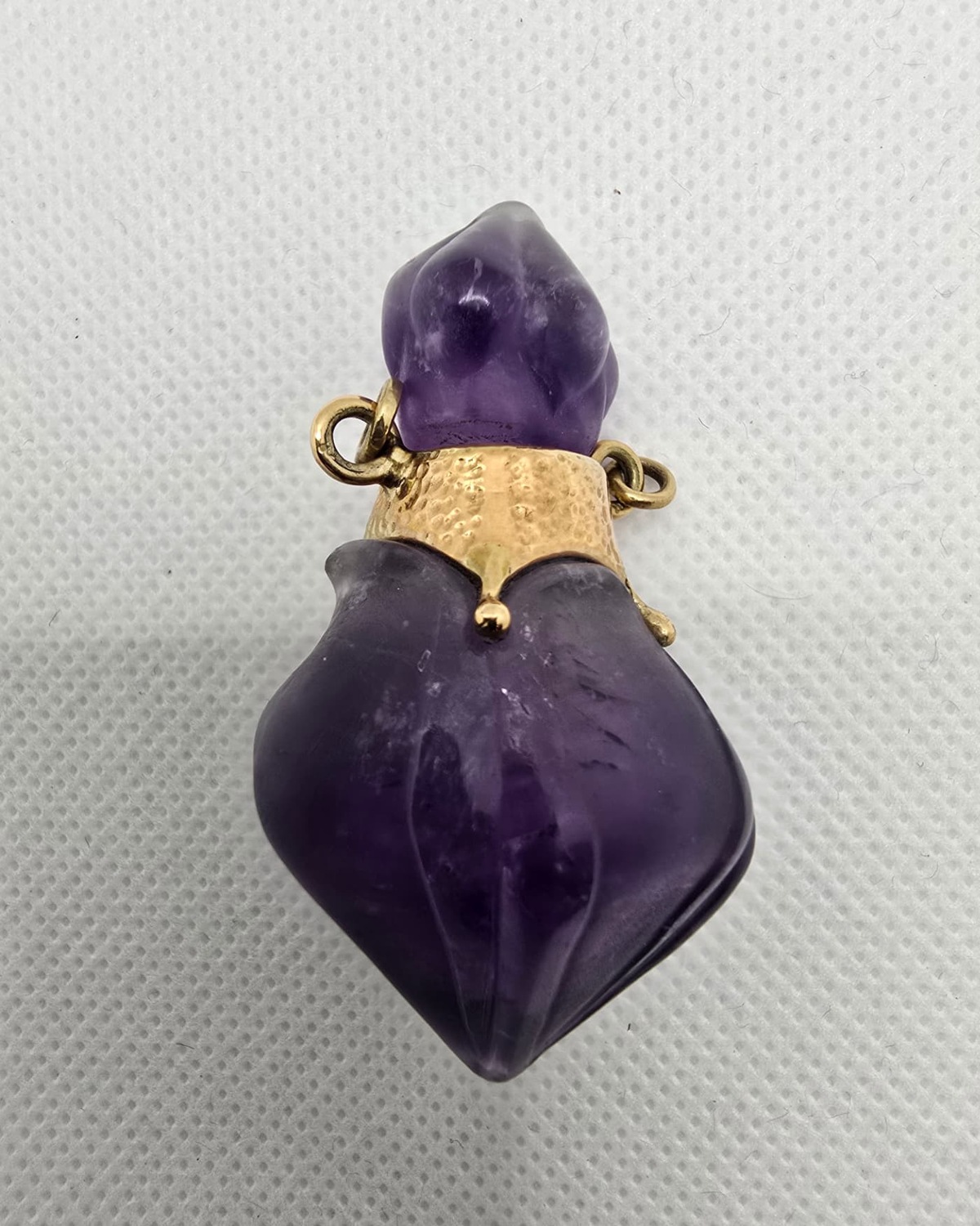 Carved amethyst vessel with gold collar, angled view showing fluting
