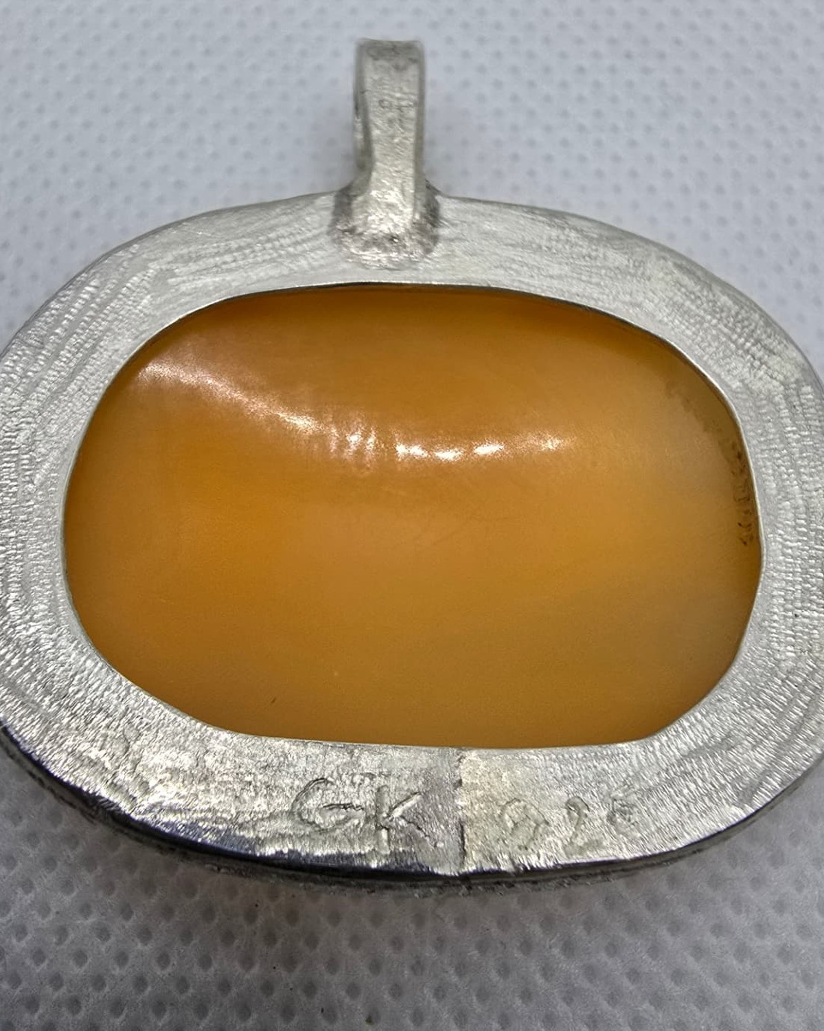 The Chariot of Victory — reverse showing the exposed naturally curved shell within the textured handmade silver frame and bail, with the engraved GK artist's mark