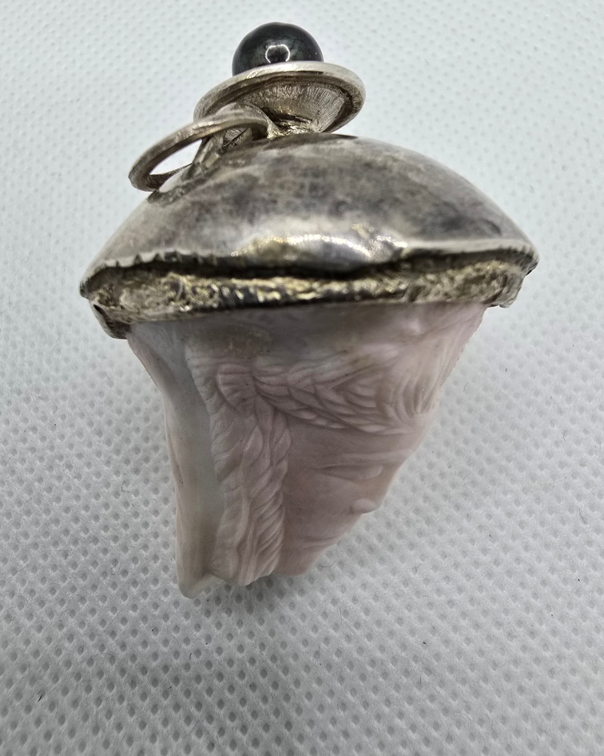Rose quartz carved face vessel, angled view showing silver cap and finial