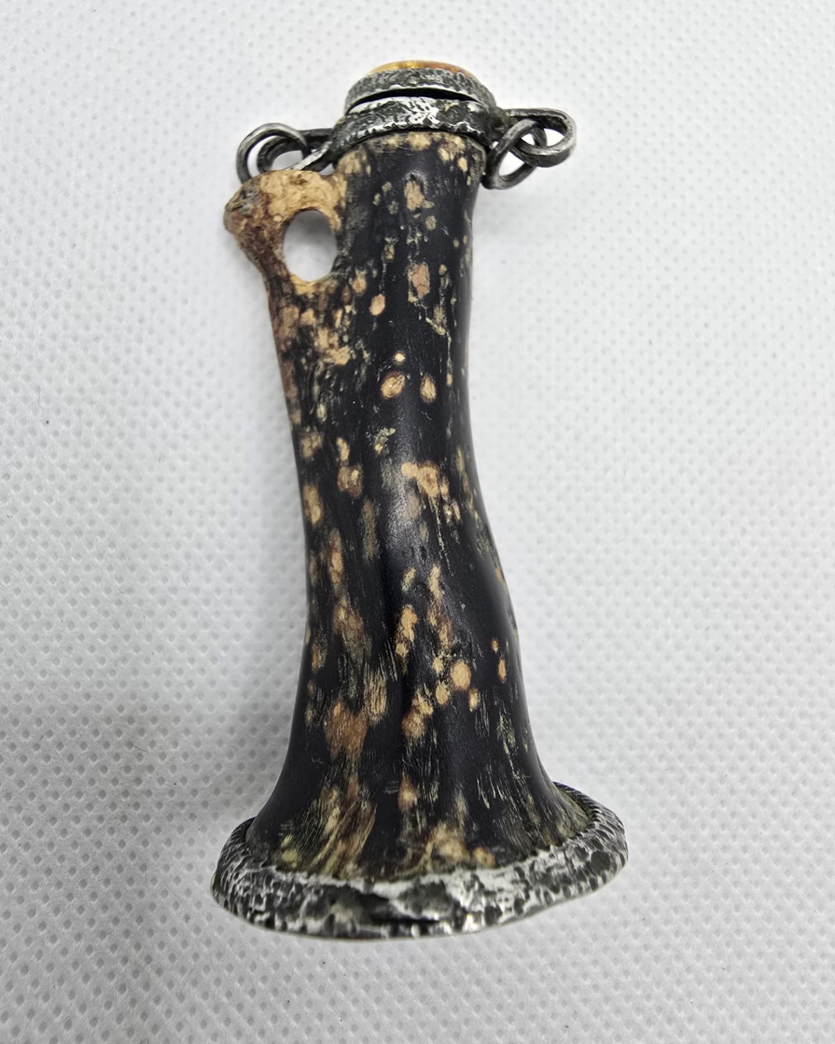 Carved antler vessel with silver collar and amber cabochon stopper, front view