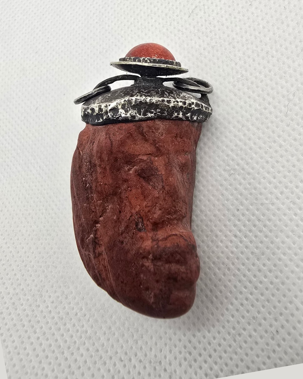 Hand-carved red stone vessel with silver mount and coral stopper, front view