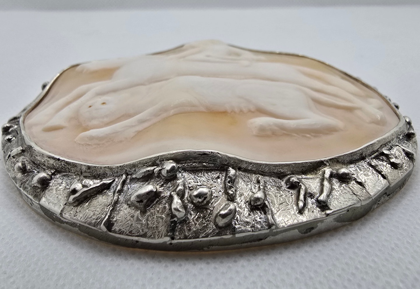 The Hunt — low-angle view showing the depth of the relief carving and the raised, textured handmade silver border