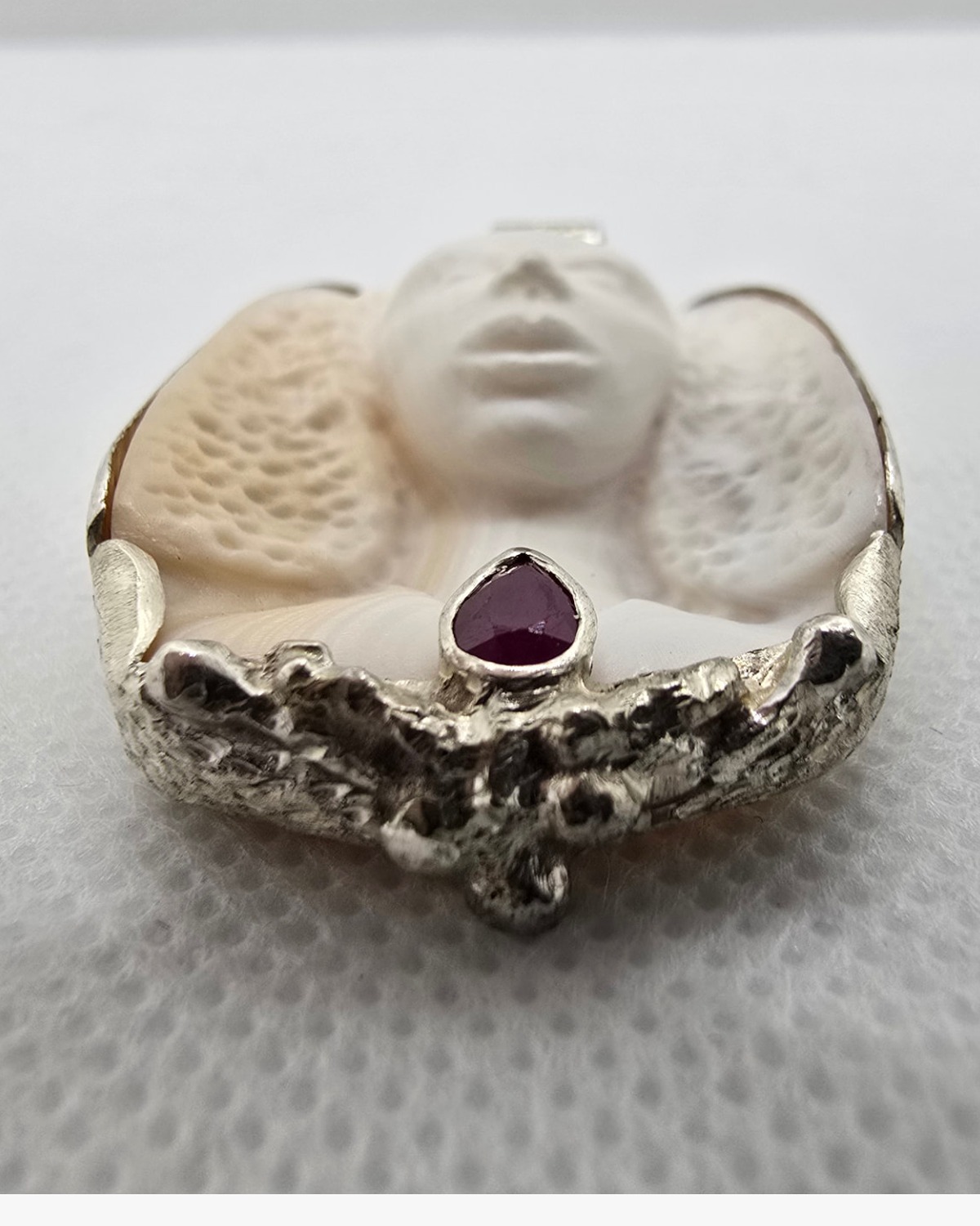 The Ruby Muse — low-angle view showing the depth of the hand carving and the raised silver ruby setting