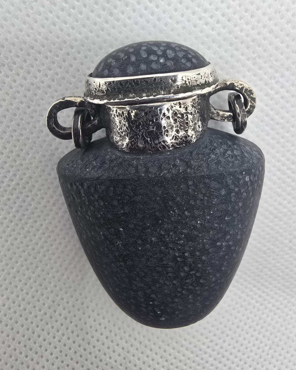 Black basalt vessel with textured silver collar and domed stopper, front view